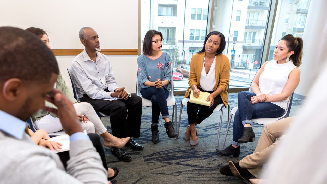 A group of people sitting in a circle talking.