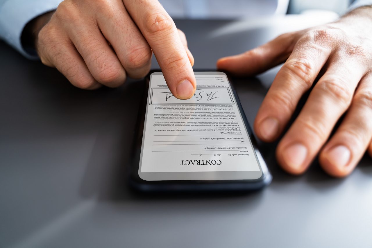man signing contract on phone