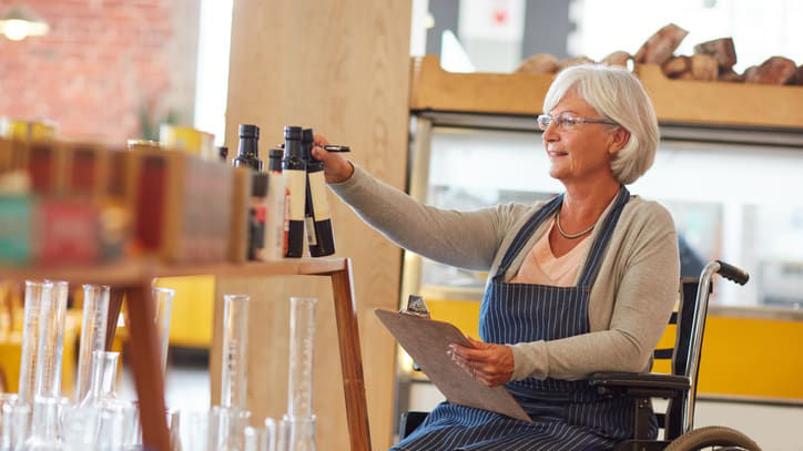 A woman in a wheelchair looking at bottles in a store.