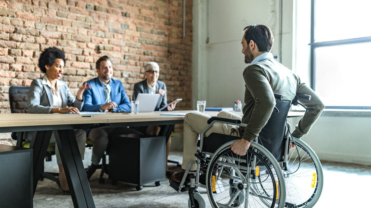 A businessman in a wheelchair sitting at a conference table.