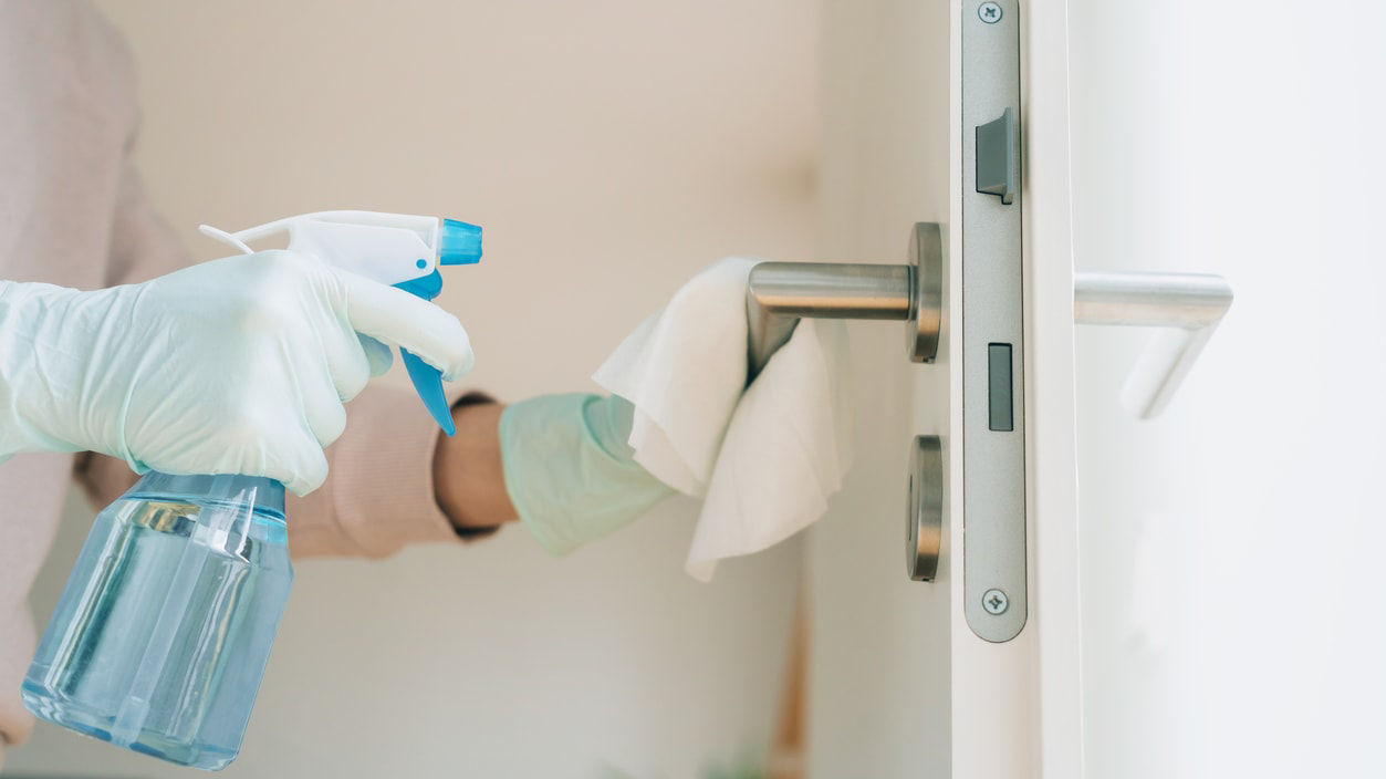 A woman cleaning a door with a spray bottle.