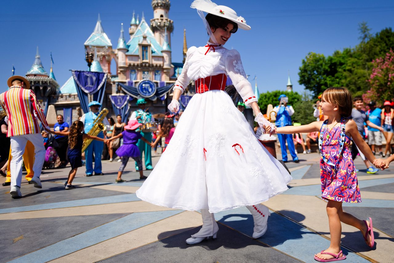 Anaheim, CA: Mary Poppins smiles at a young child as she leads a line of children in song and dance in front of Cinderella's castle during Disney's 60th Diamond Celebration.