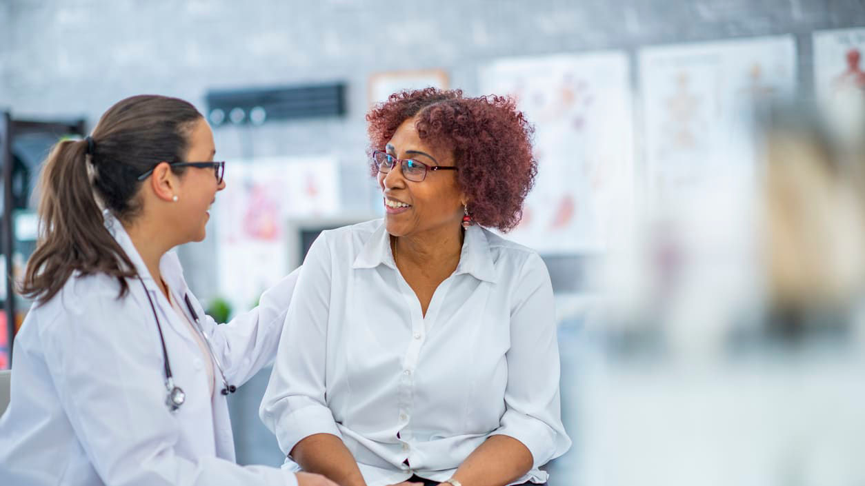 Two women talking to a doctor in a doctor's office.