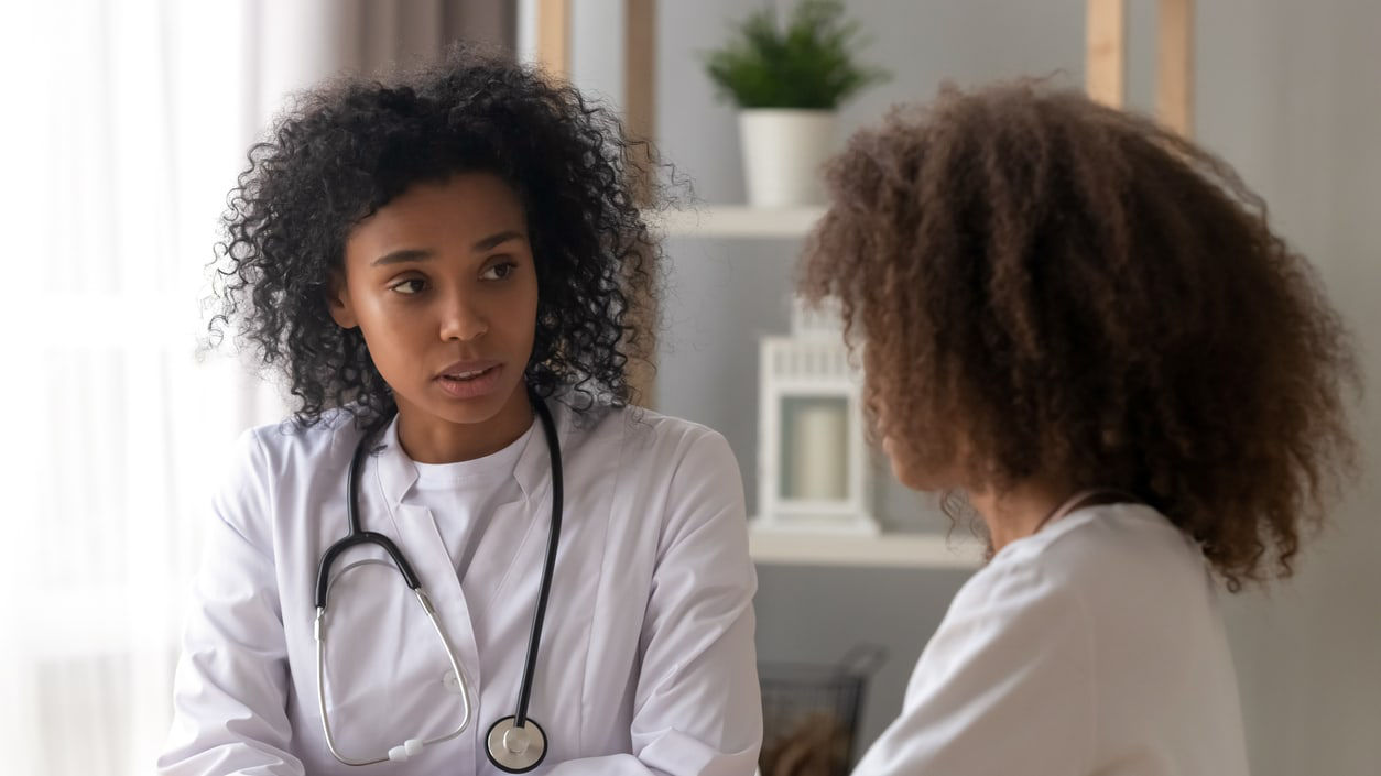 A female doctor talking to a female patient in a doctor's office.