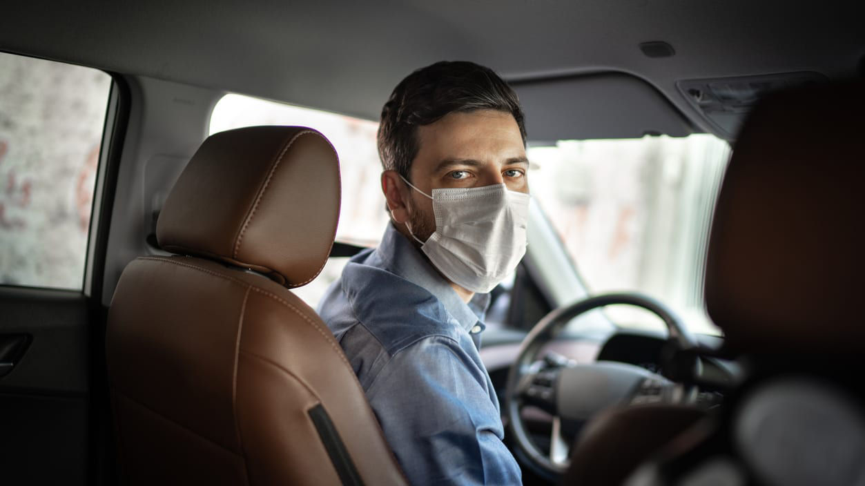 A man wearing a face mask in a car.