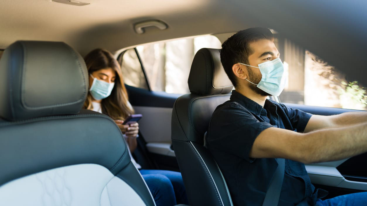 Two people wearing face masks in a car.