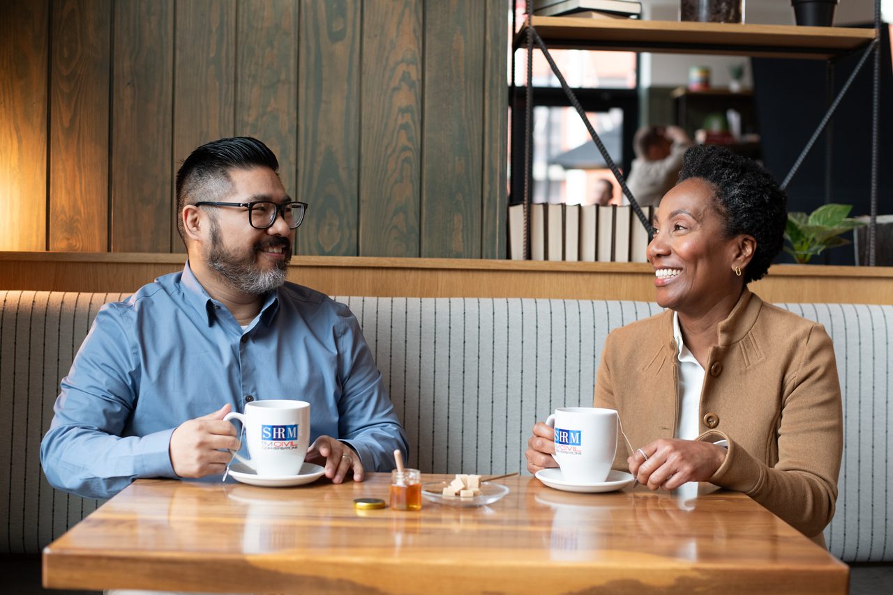 Two people chat over tea