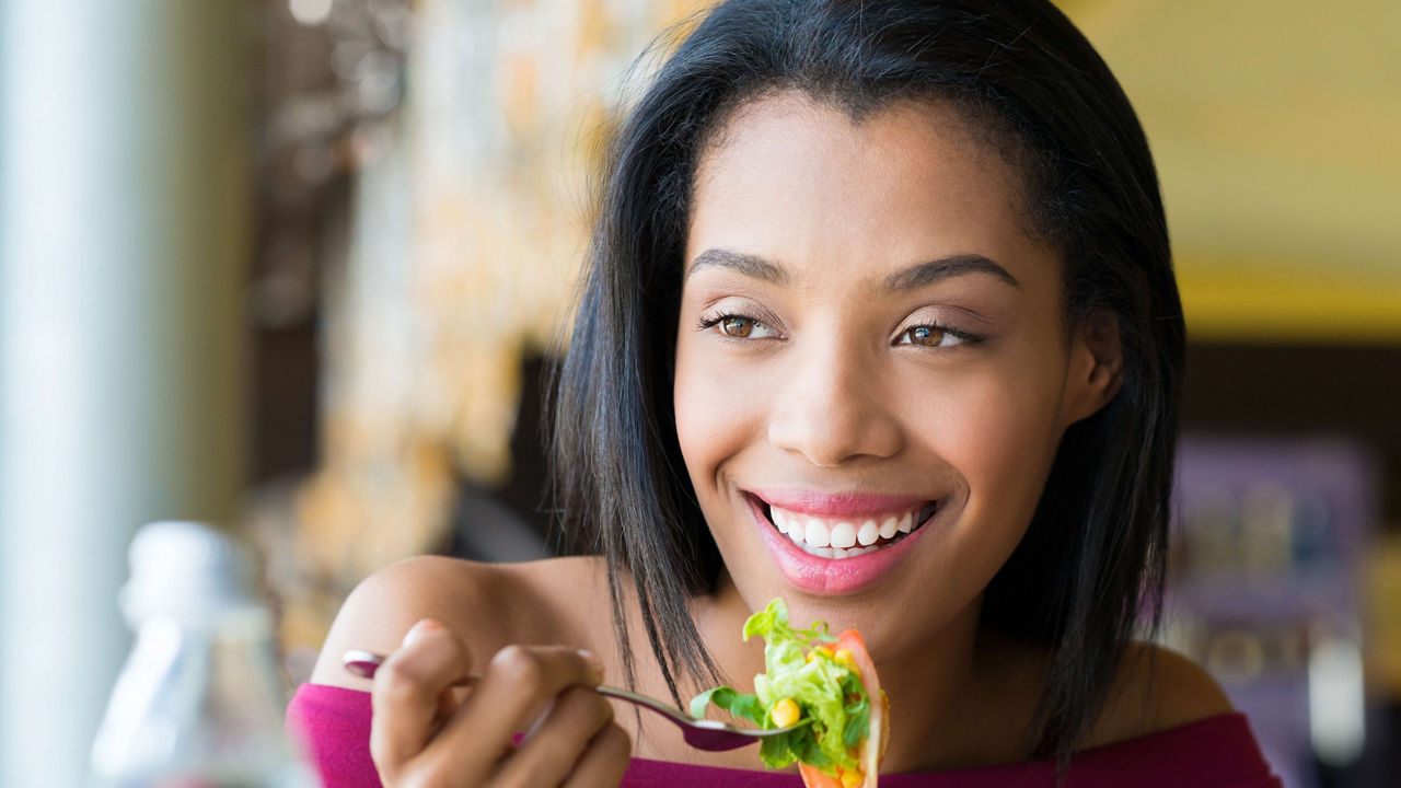 A woman is eating a salad in a restaurant.