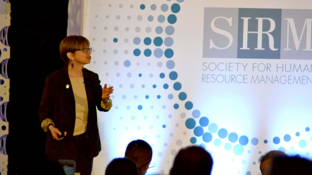 A woman giving a presentation at the society for human resource management.