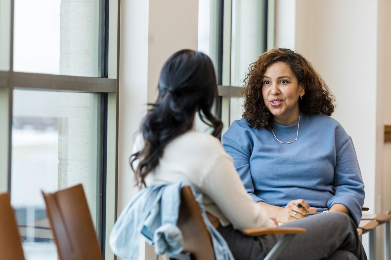 Smiling female executive speaks to colleague whose back is to the camera