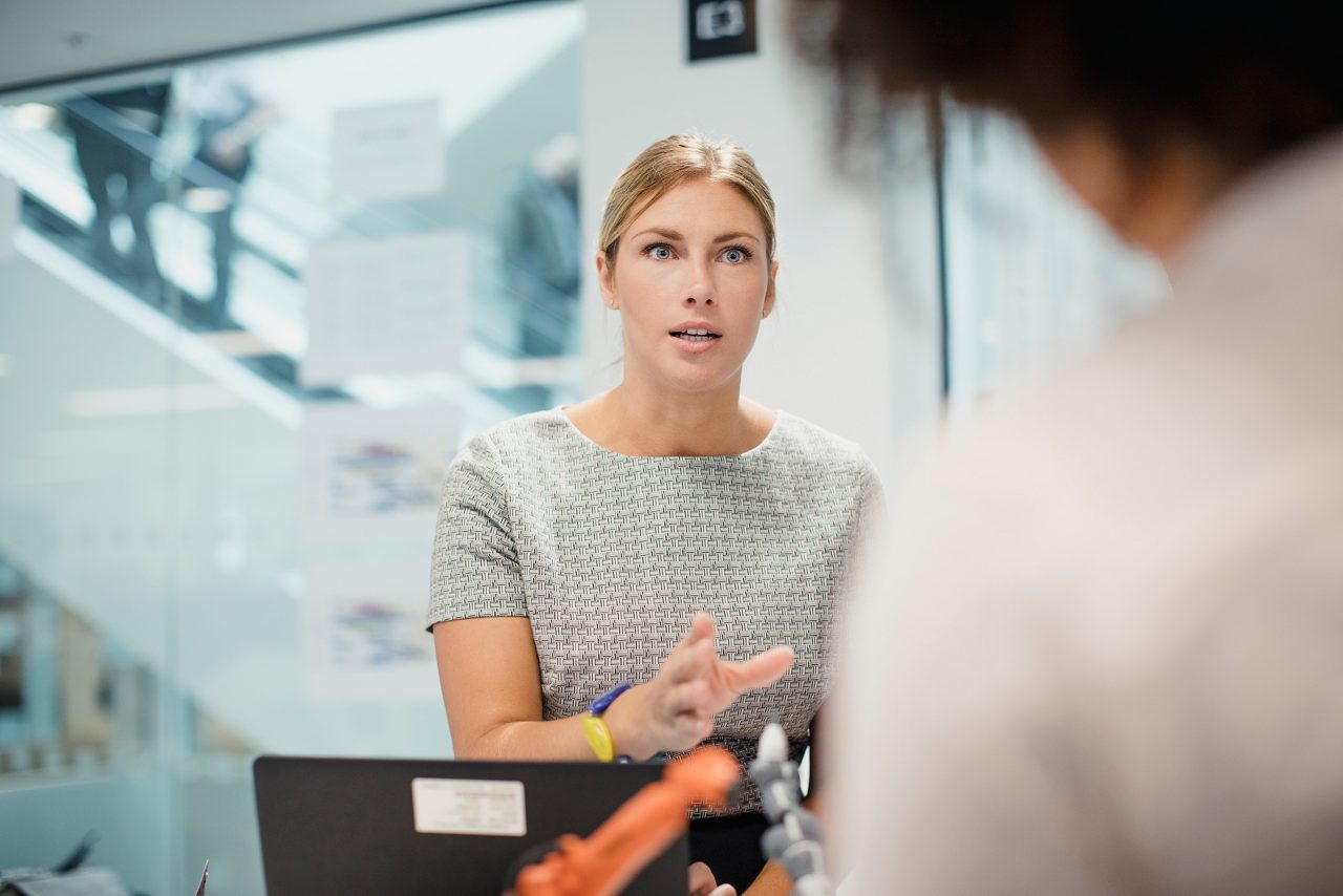 Woman speaking seriously to other workers in office 