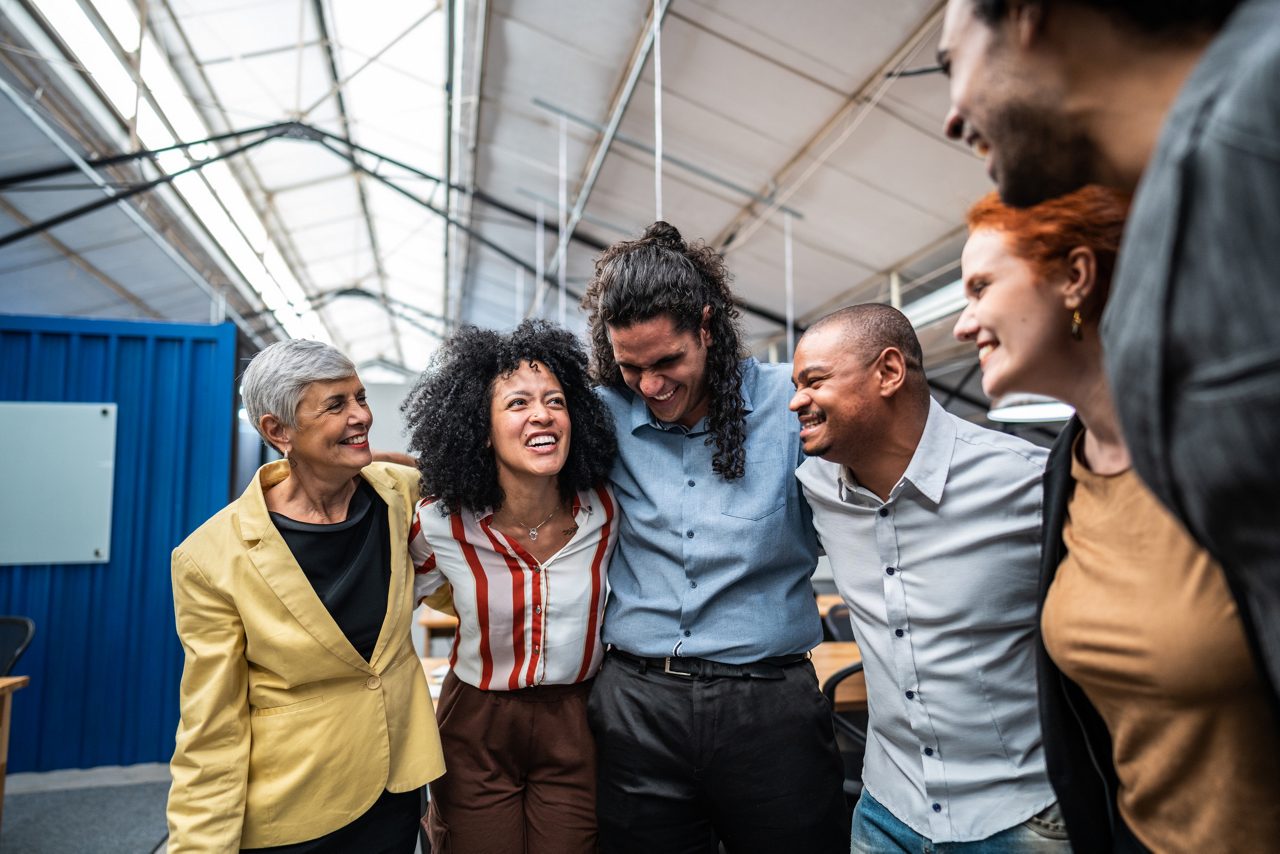 Coworkers embracing and celebrating at office