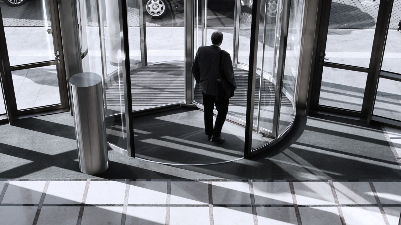 man walking out revolving door