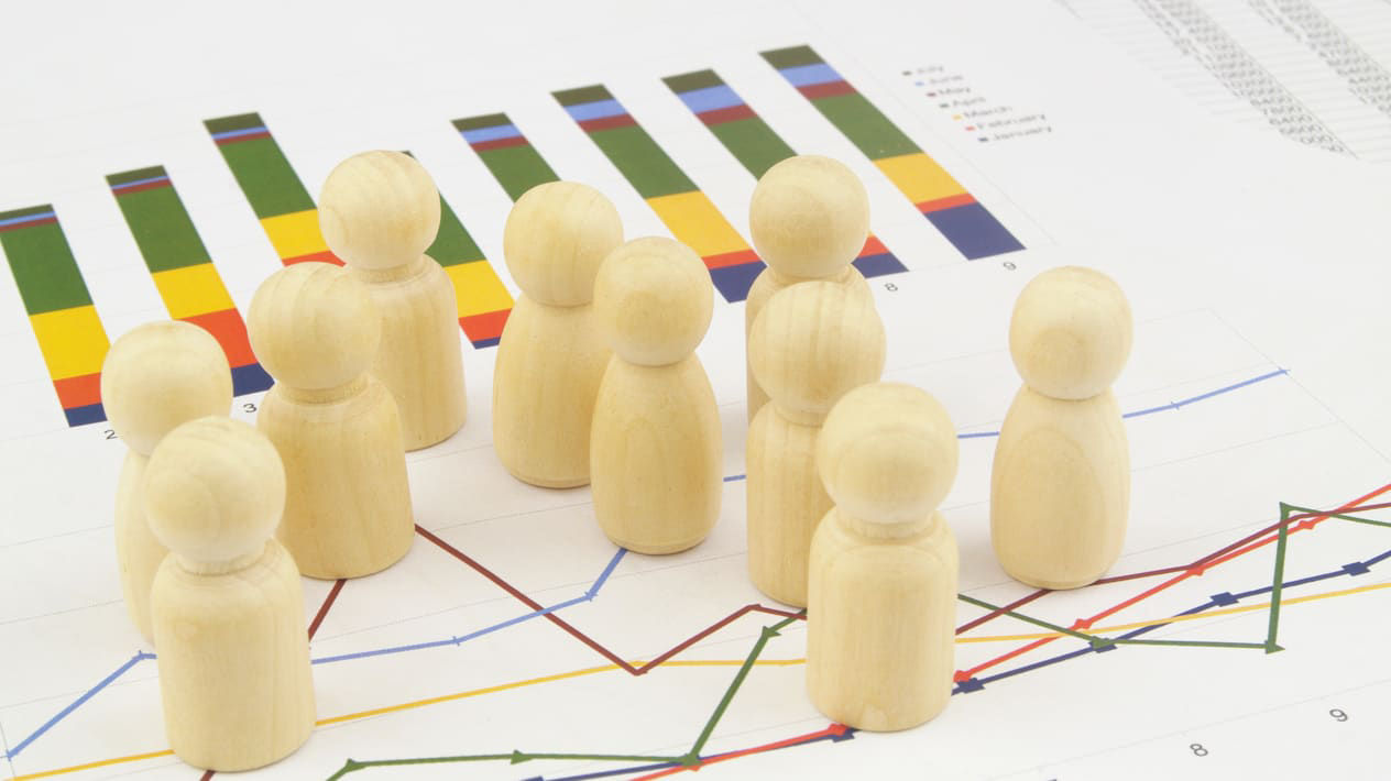 A group of wooden figures standing in front of a graph.