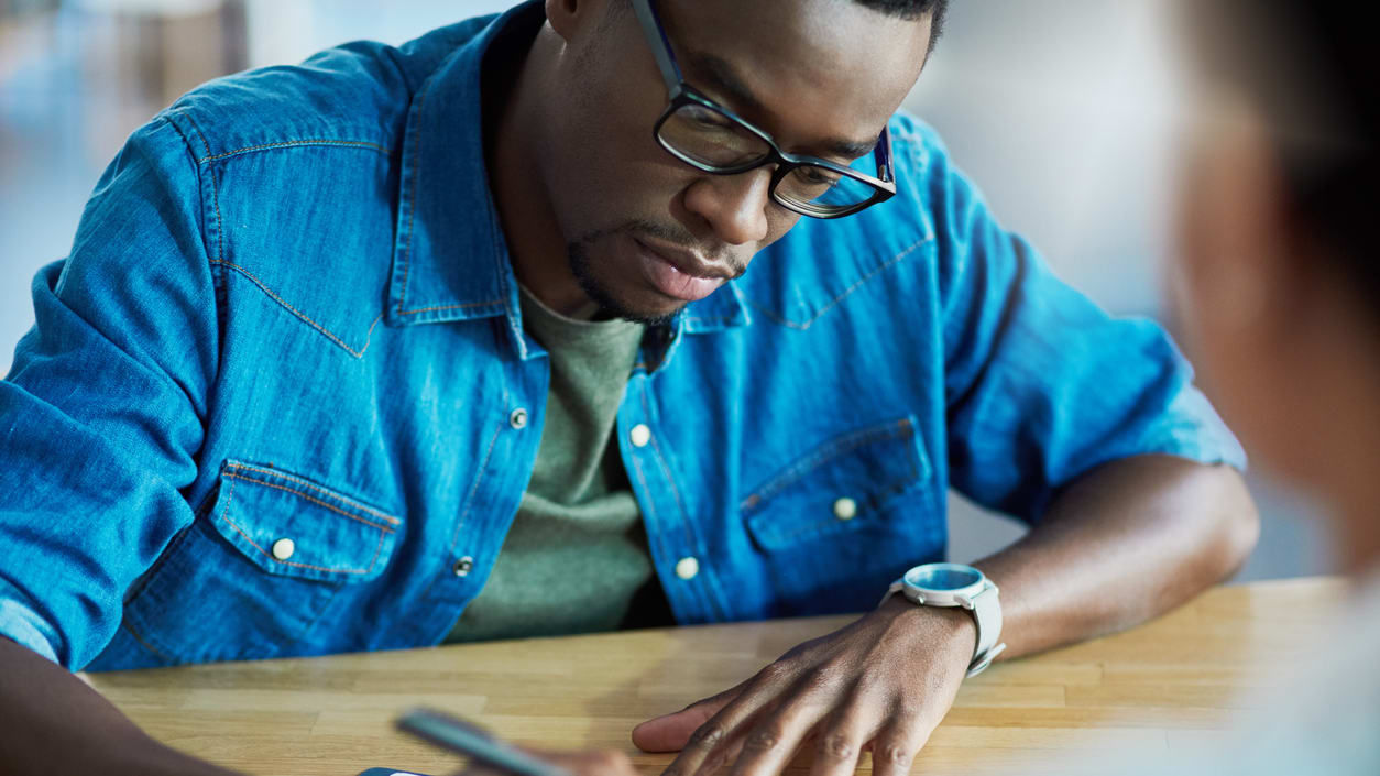 A man is signing a document at a table.