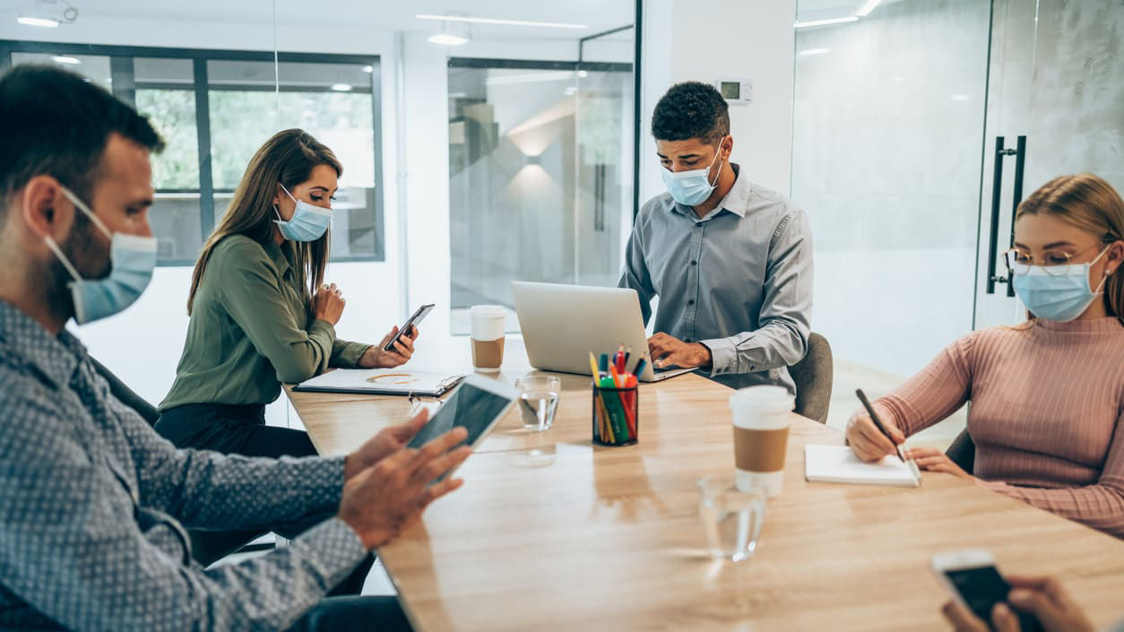 A group of people wearing face masks at a conference table.