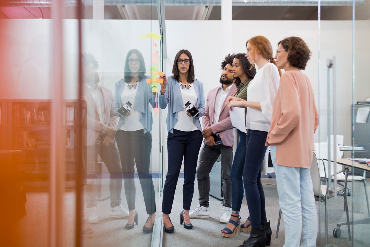 Business people brainstorming in conference room with adhesive notes.