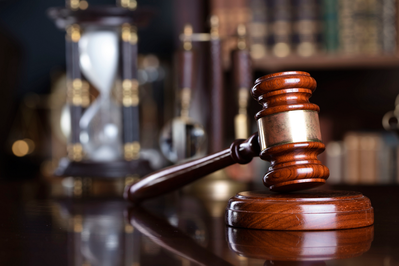 Gavel and scale on the judge desk. Book shelf  in the background.