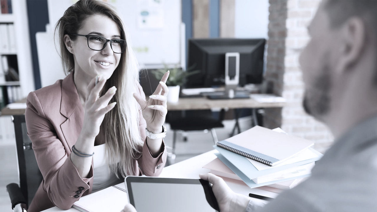 A woman is talking to a man in an office.