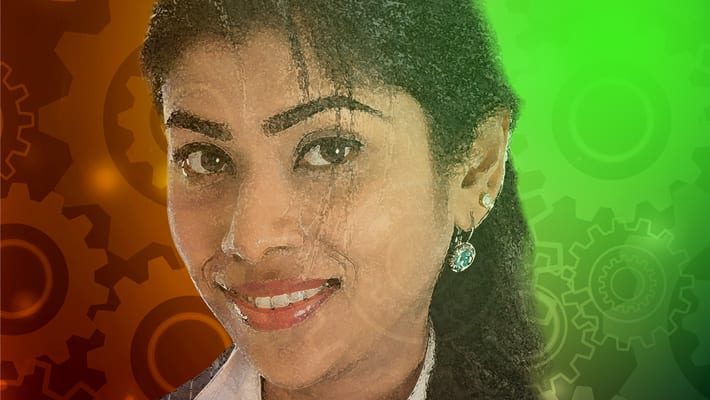 An indian woman smiling in front of a colorful background.