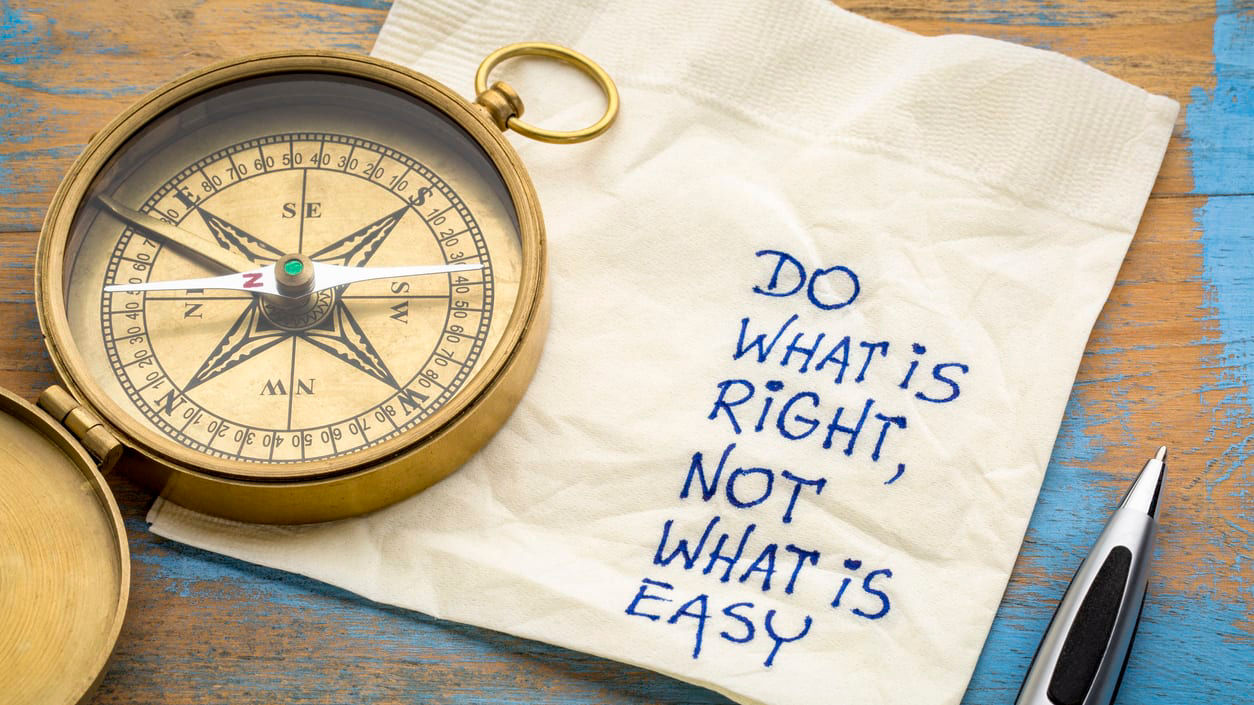 A compass laying on top of a napkin that has the words "Do what's right, not what's easy" written on it.