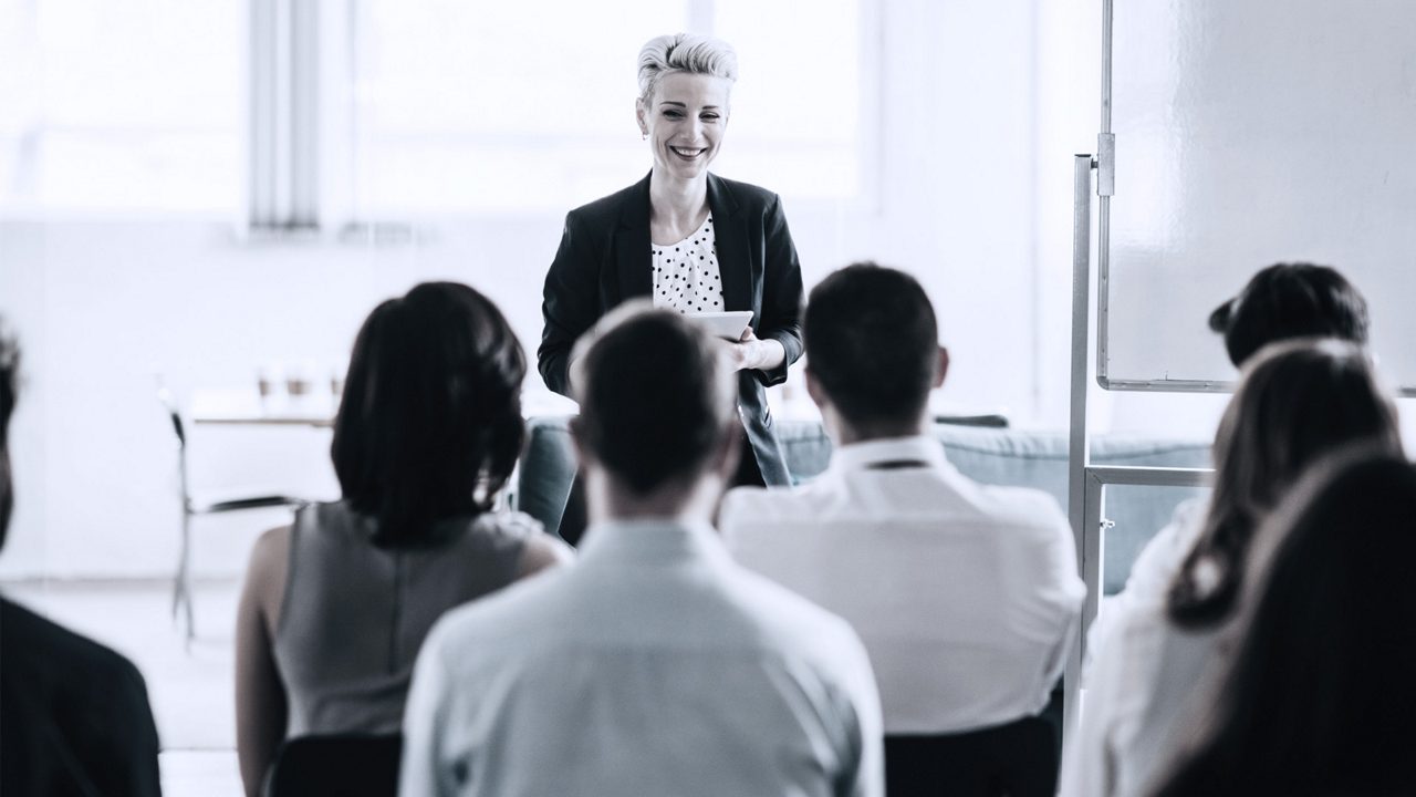 Business leader presenting to a seated crowd of employees.