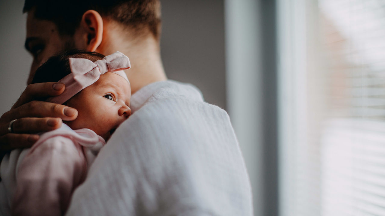 A man is holding a baby girl in his arms.