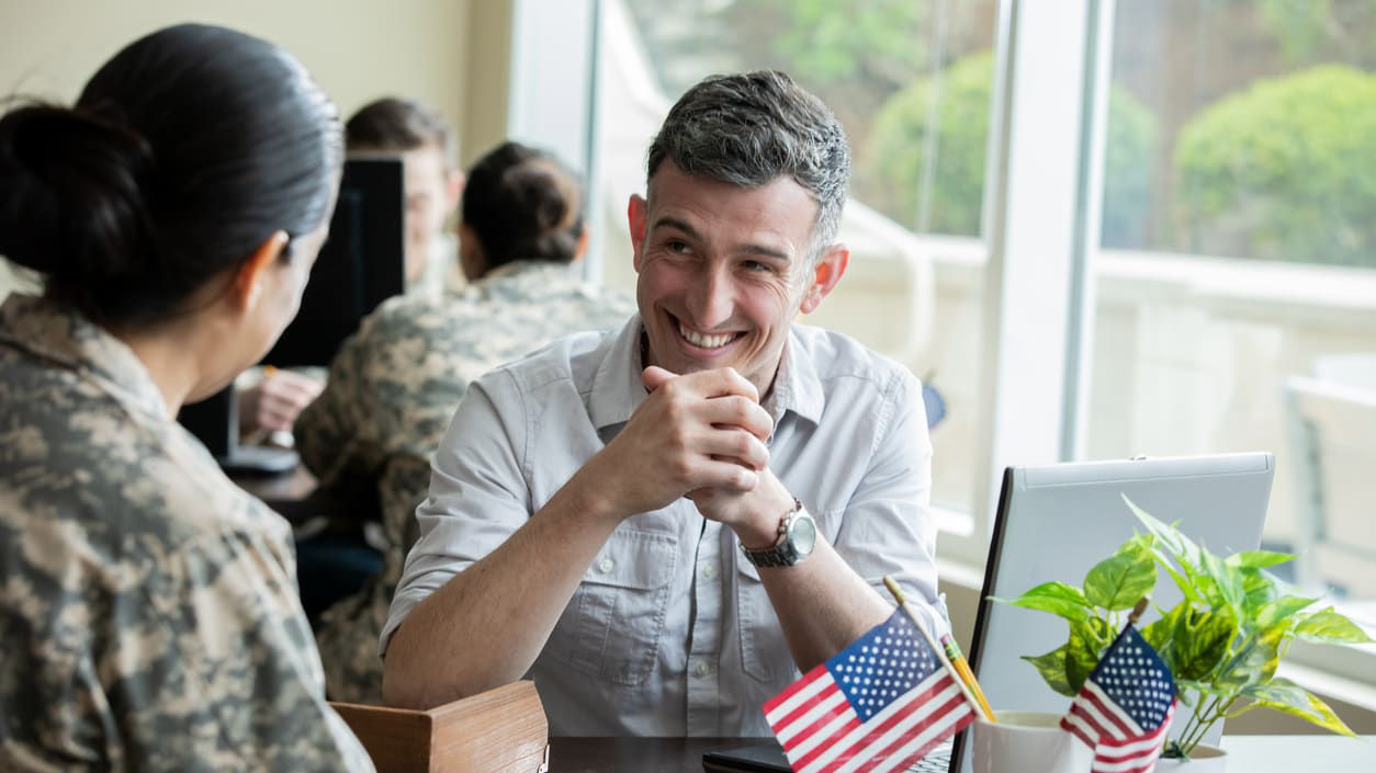 A man and woman talking at a table with american flags.