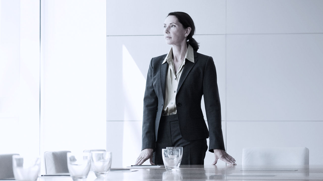 Female standing at boardroom table looking out window