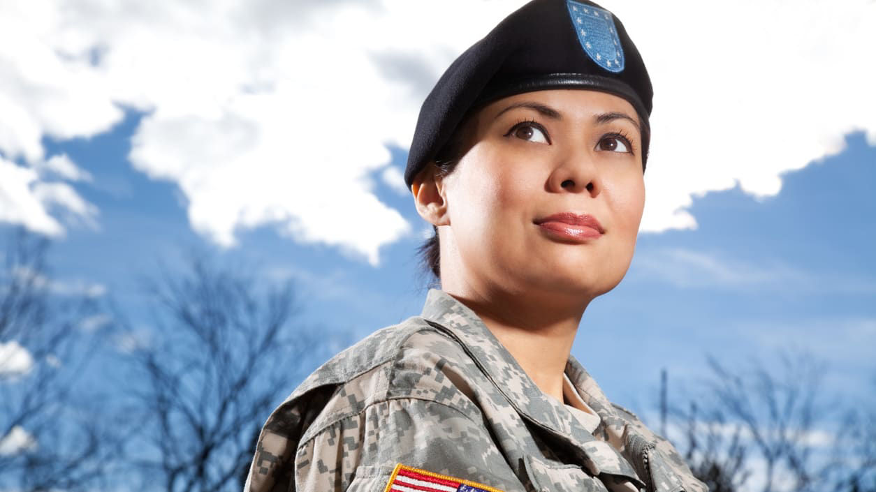 A woman in uniform is looking up at the sky.