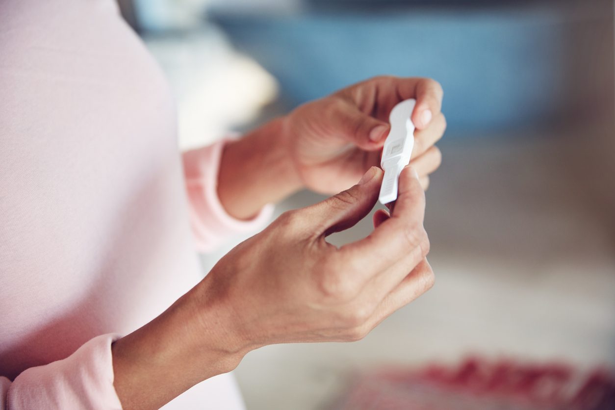 close up of a woman holding a pregnancy test