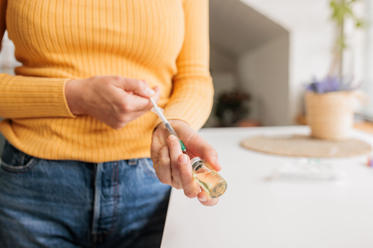 woman drawing medicine from vial into a syringe for injection