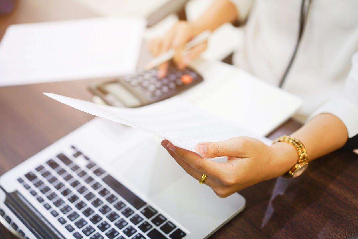 closeup of a woman looking at papers and using a calculator