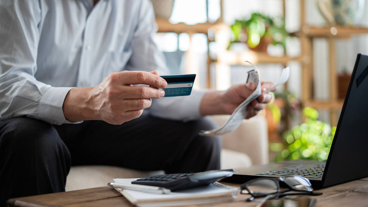 closeup of man holding bills and a credit card