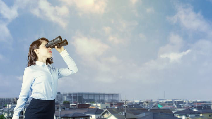 A business woman looking through binoculars.