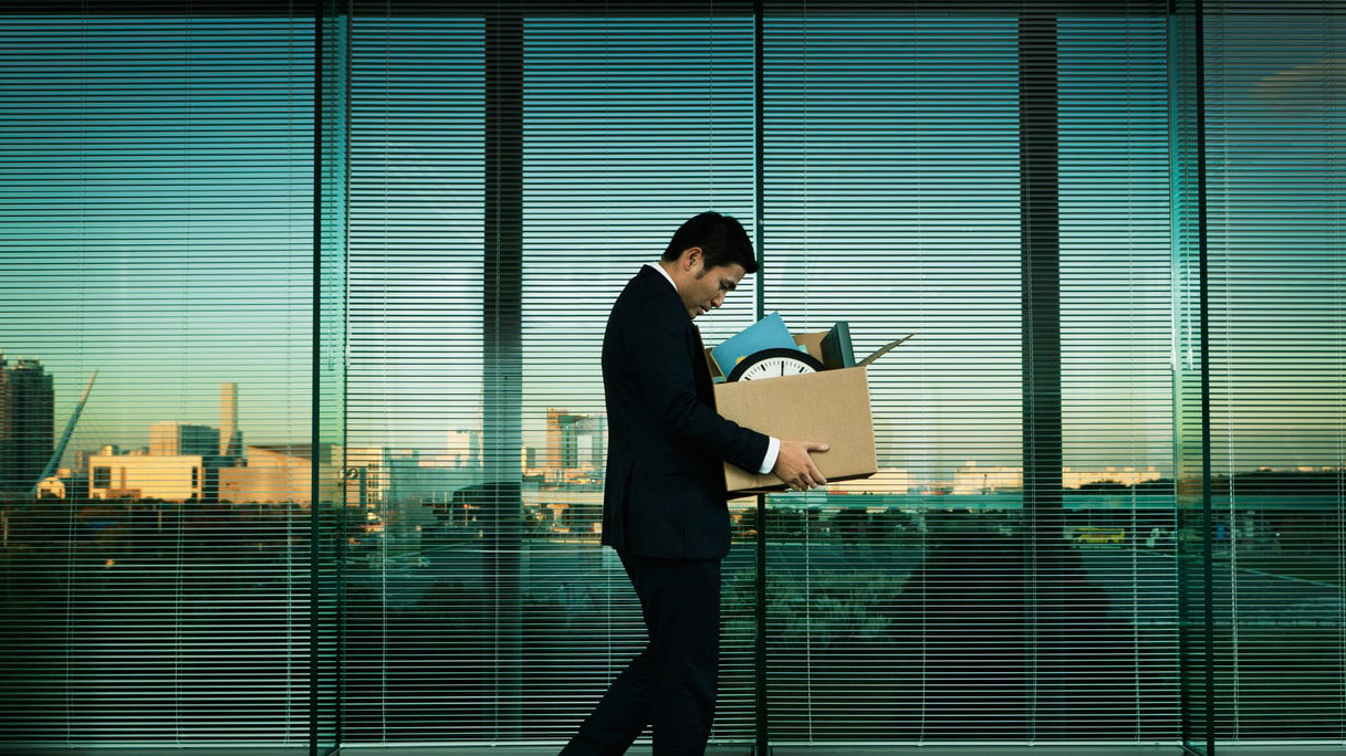 A businessman carrying a box in front of a window.
