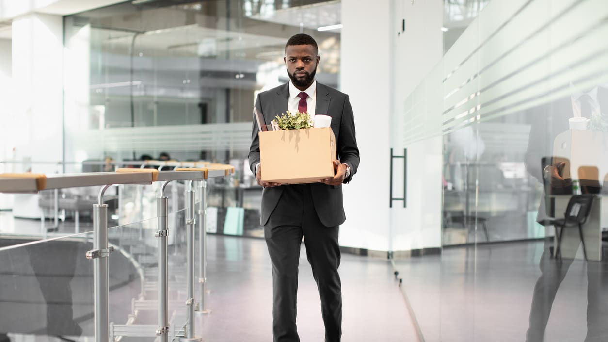 A man in a suit carrying a box in an office.