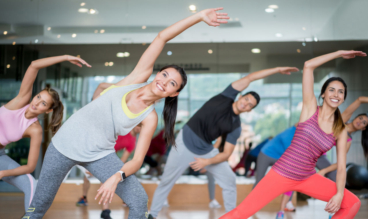Group of people in an aerobics class at the gym stretching looking very happy â   fitness concepts