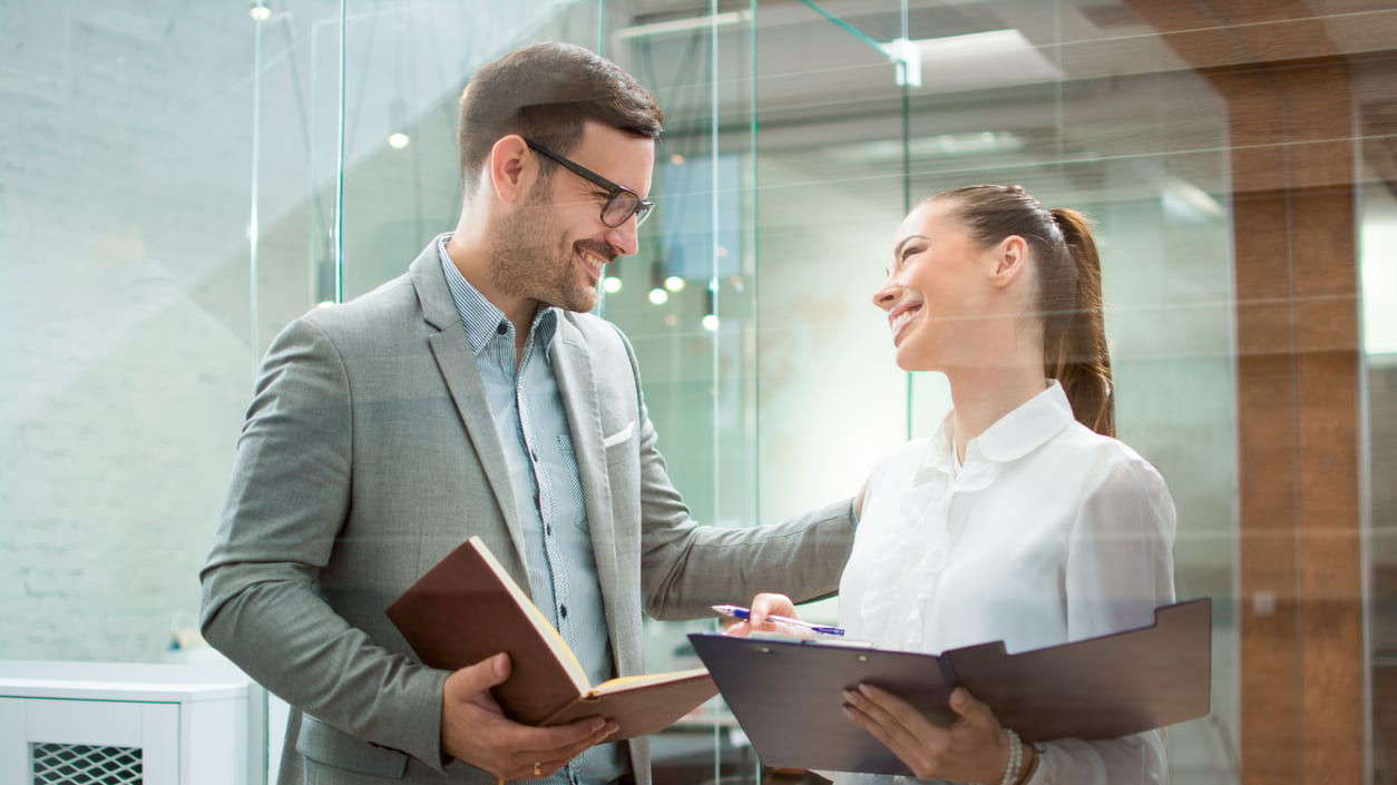 A businessman and a woman talking in an office.