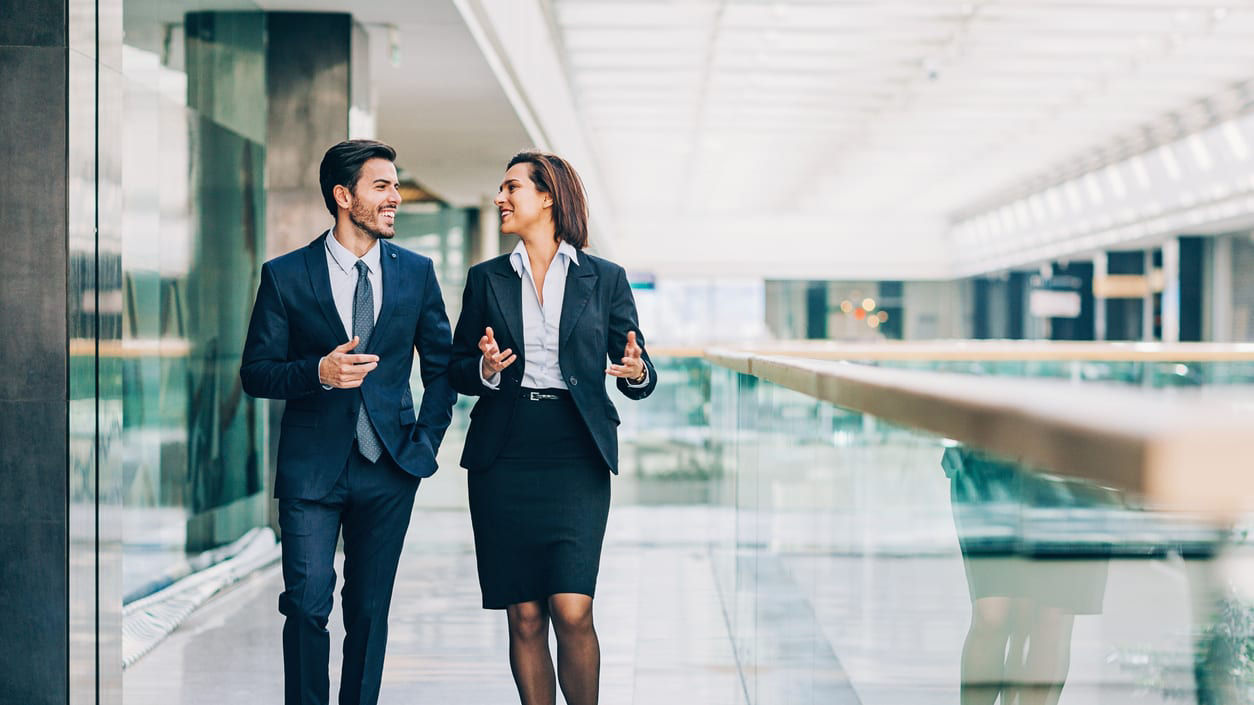 Two business people walking in an office building.