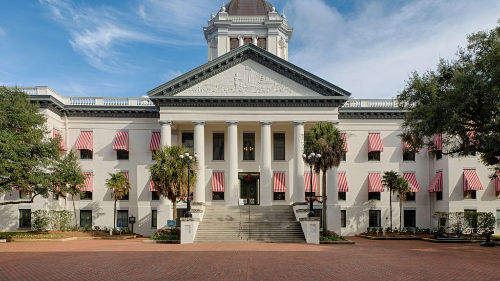 A large building with columns and a pink awning.