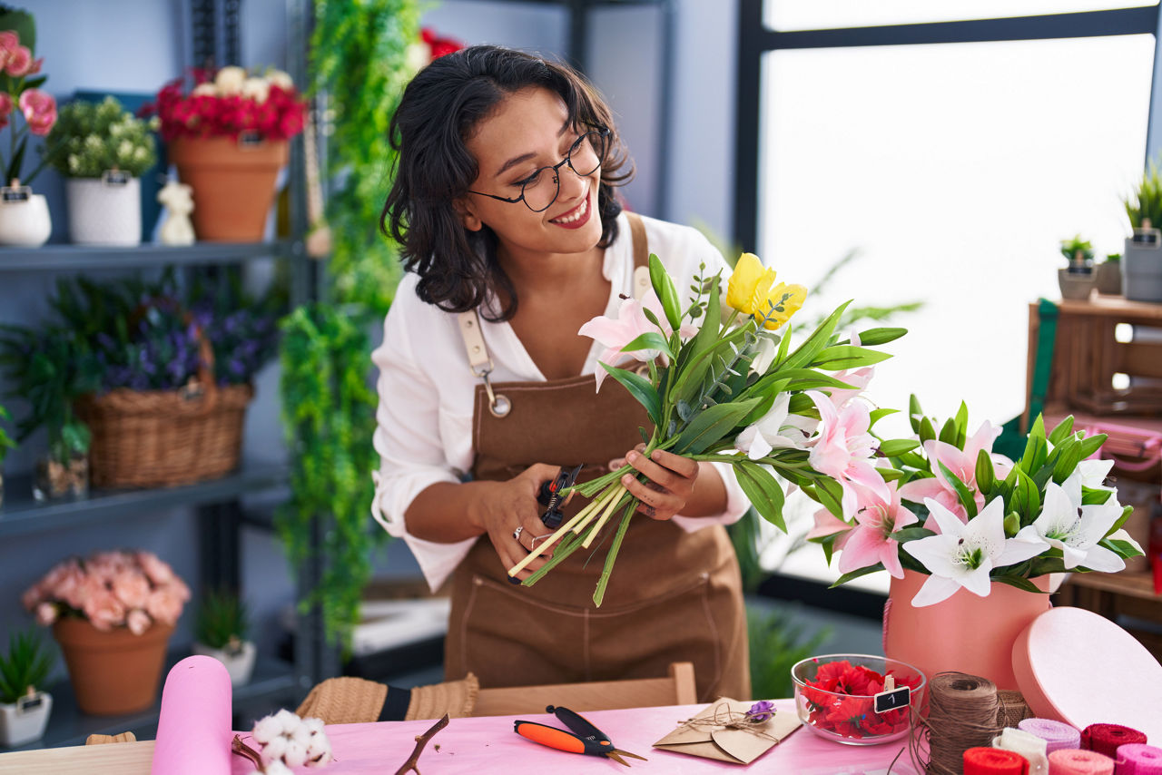 Young woman florist make bouquet of flowers at flower shop