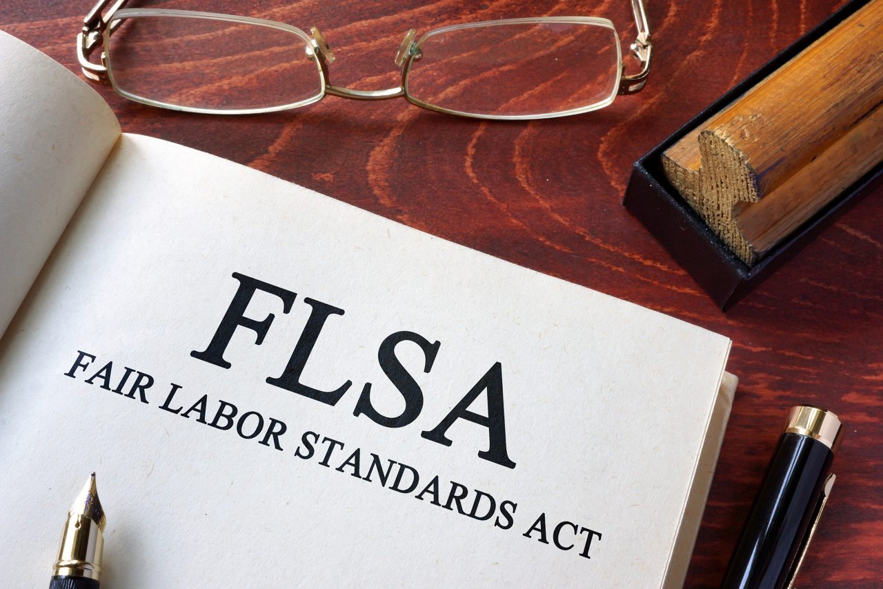 Page with FLSA fair labor standards act printed on it, on a table with a pen and glasses.