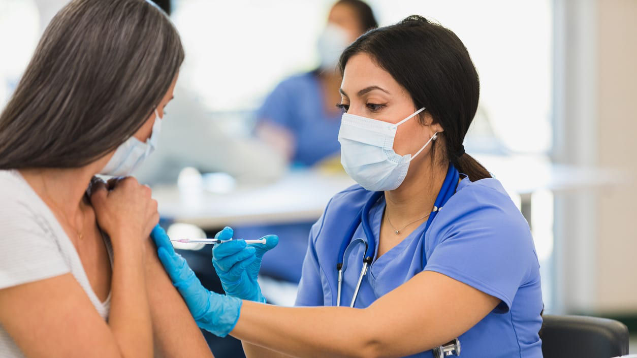 A nurse is giving a woman a vaccine.