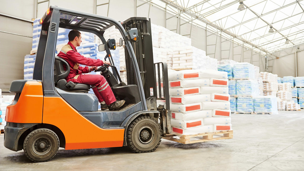 A worker is driving a forklift in a warehouse.