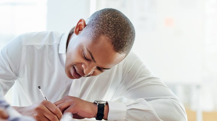 A businessman signing a document at a table.