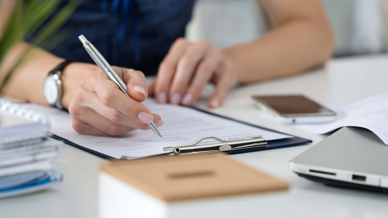 A woman is writing on a piece of paper with a pen.