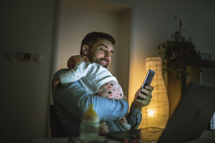 Young father working at home with his baby  girl