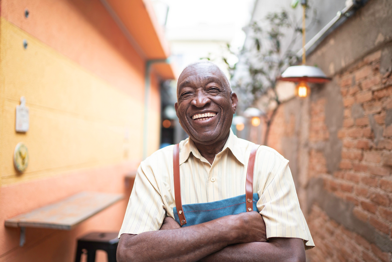 Portrait of smiling elderly waiter looking at camera
