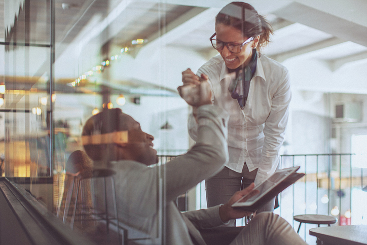 Young businessman and businesswoman giving each other a high five in a modern office space